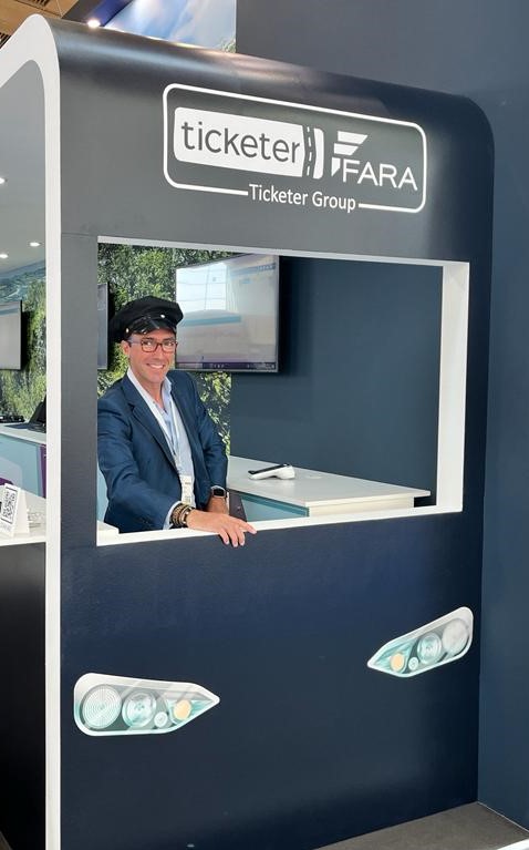 Antonio Carmona wearing bus conductors hat at Ticketer Group stand which looks like the front of a bus at IT-Trans conference 2022